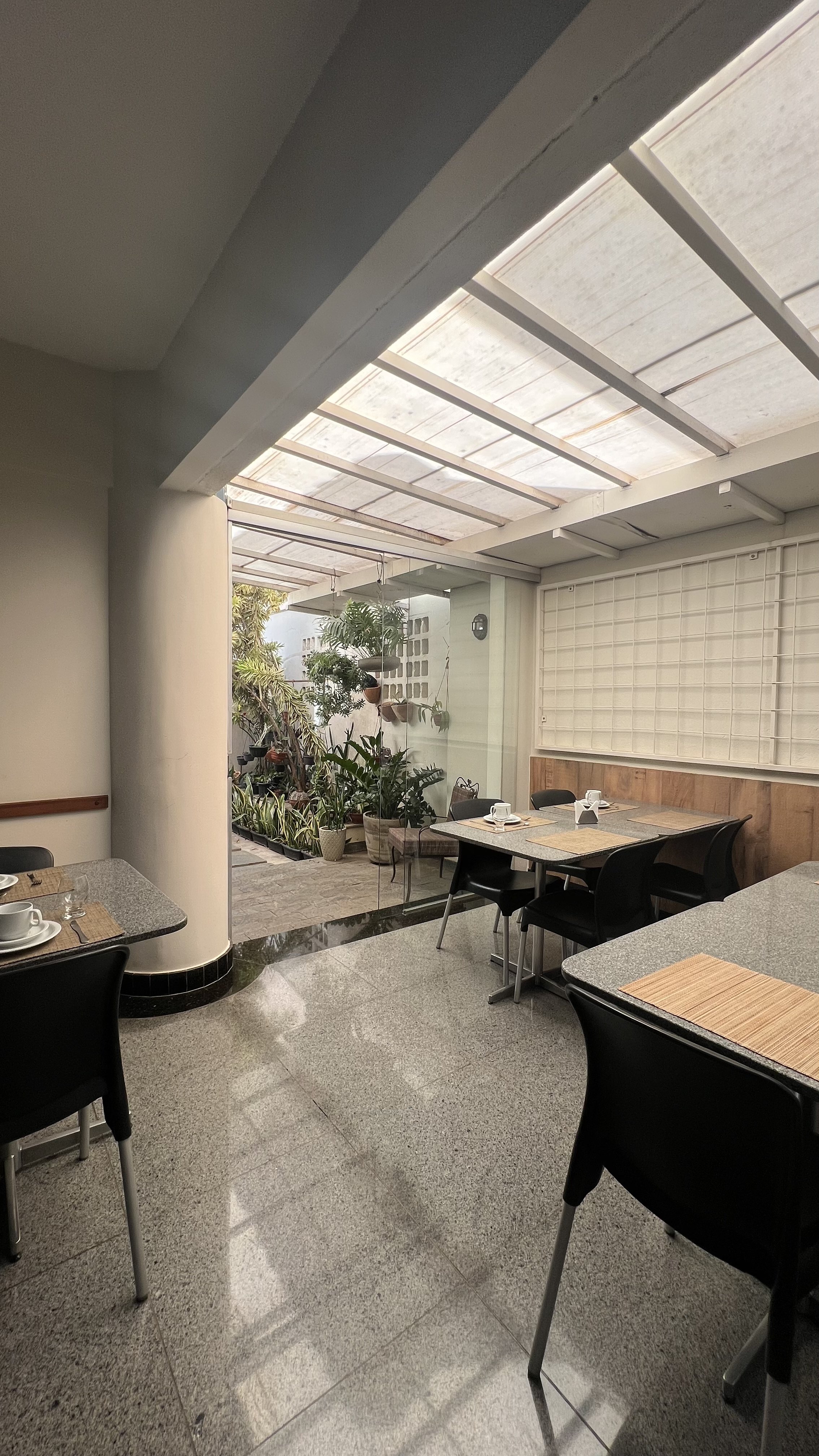 Área do café da manhã com mesas e jardim interno