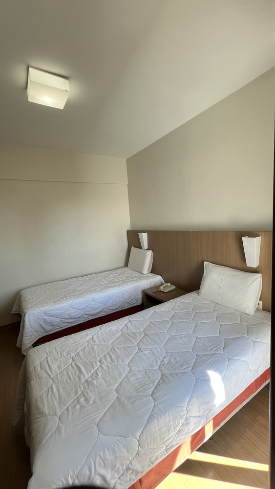 Quarto do Residence Hotel com duas camas de solteiro, mesa de cabeceira e ar-condicionado